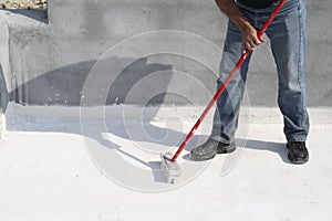 Worker applying white roof coating photo