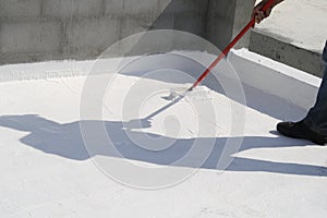 Worker applying white roof coating photo
