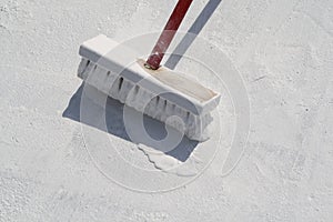 Worker applying white roof coating photo