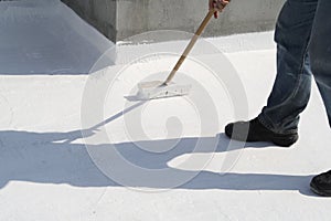 Worker applying white roof coating photo