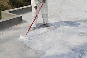 Worker applying white roof coating photo