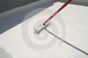 Worker applying white roof coating photo