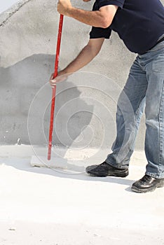 Worker applying white roof coating photo