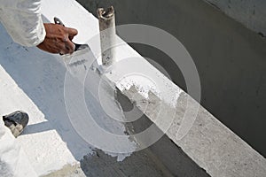 Worker applying white roof coating photo