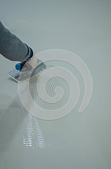 Worker applying a white epoxy resin bucket on floor