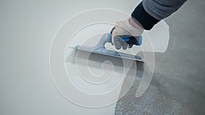 Worker applying a white epoxy resin bucket on floor