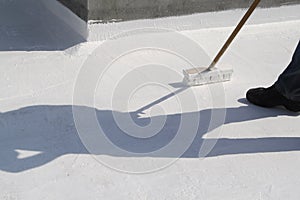 Worker applying white roof coating