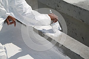 Worker applying white roof coating