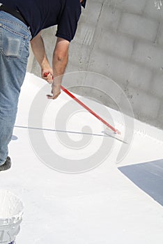 Worker applying white roof coating