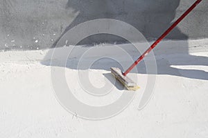 Worker applying white roof coating photo