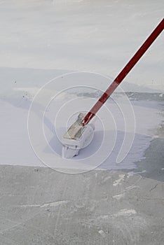 Worker applying white roof coating photo