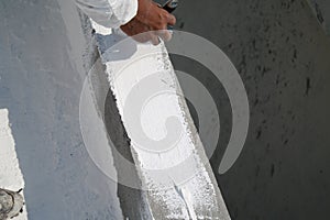 Worker applying white roof coating photo