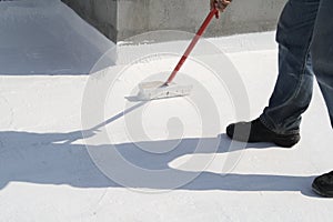 Worker applying white roof coating