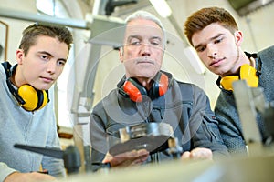 worker and apprentices with earmuffs