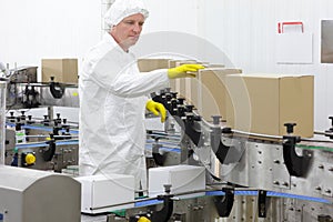 Worker in apron, cap at production line in factor