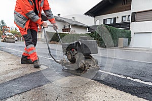 Worker at asphalting with vibrator