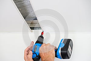 Worker assemble a suspended ceiling and fixing panel with an screwdriver