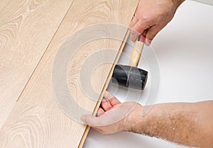 Worker assembling laminate floor using a hammer