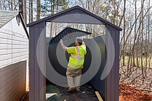 Worker assembling plastic vinyl storage sheds for backyards near his home in an assembly line process