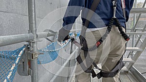 A worker attaches his full body harness to the scaffold photo