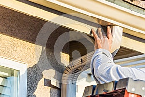 Worker Attaching Aluminum Rain Gutter and Down Spout to Fascia of House