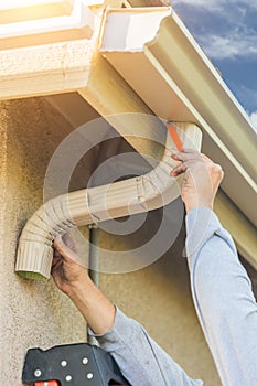 Worker Attaching Aluminum Rain Gutter and Down Spout to Fascia o