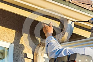 Worker Attaching Aluminum Rain Gutter and Down Spout to Fascia o