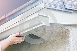 Worker Attaching Aluminum Rain Gutter to Fascia of House