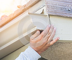 Worker Attaching Aluminum Rain Gutter to Fascia of House.