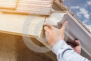 Worker Attaching Aluminum Rain Gutter to Fascia of House.