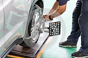 Worker attaching wheel alignment device equipment onto wheel car