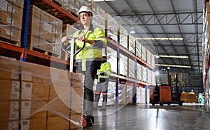 Worker in auto parts warehouse use a handcart to work to bring the box of auto parts into the storage shelf