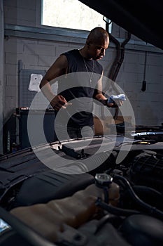 Worker of automobile repair shop cleaning gauge to check the oil level