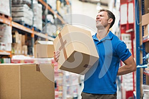 Worker with backache while lifting box in warehouse photo