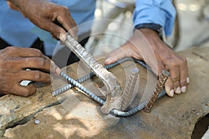 Worker bend steel rod using bender at a construction site