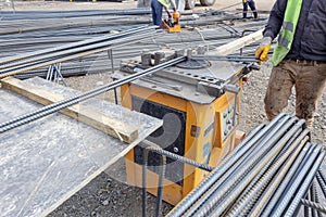 The worker is bending rebars rods in the construction site.