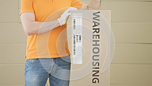 Worker and big carton with WAREHOUSING text on it