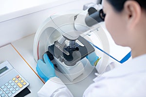 Worker of biochemical laboratory looking in microscope