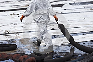 A Worker in biohazard suits used Oil Containment boom as cleani