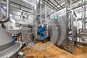 Worker in a blue robe and a cap inspect the production department of dairy factory