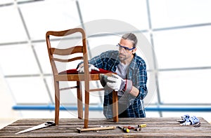 Worker in blue shirt repair old chair