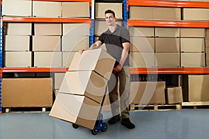 Worker With Boxes On Hand Truck In Warehouse