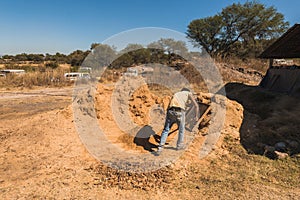 Worker of a brick factory strains sand with a  in a wheelbarrow, for the elaboration of bricks