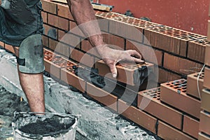 Worker or bricklayer laying bricks. Builder makes brickwork on construction site, close up on hands