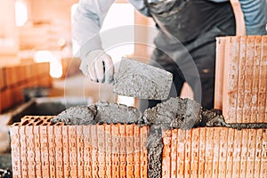 worker, bricklayer or mason laying bricks and creating interior walls. Detail of level trowel