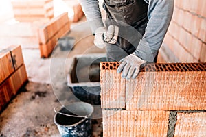 worker, bricklayer and mason working with bricks and building interior walls of house