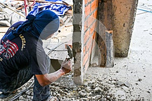 Worker bricklayer scooping mixed mortar brick to install bricks block on construction site