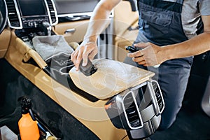 Worker with brush wipes car armrest, dry cleaning