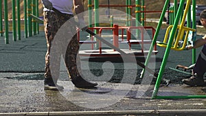 A worker brushes cover concrete, bitumen-rubber primer.