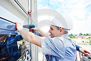 Worker builder installing glass windows on facade